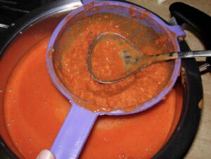 Preparazione della marmellata di rosa canina con colino per filtrarla