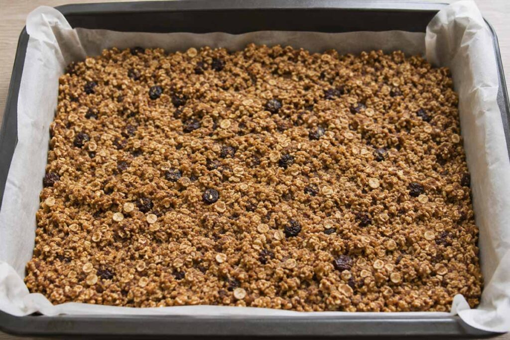 Composto per barrette ai cereali vegan in teglia_edited Composto per barrette ai cereali vegan steso in una teglia con carta forno