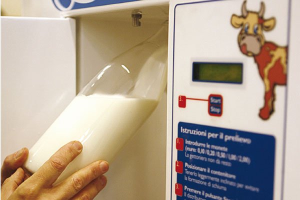 Bottiglia di vetro parzialmente riempita con latte crudo direttamente dal distributore automatico