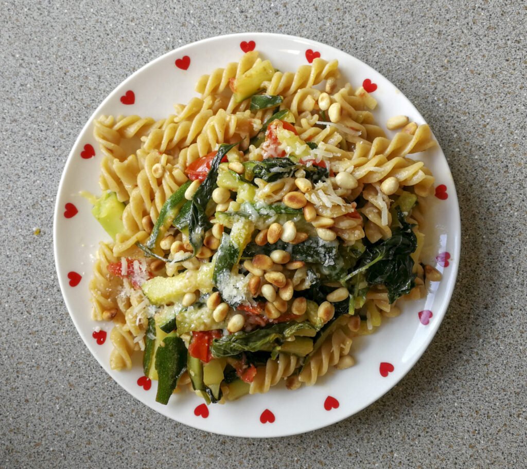 Piatto con fusilli con spinacio rampicante, zucchine e pinoli