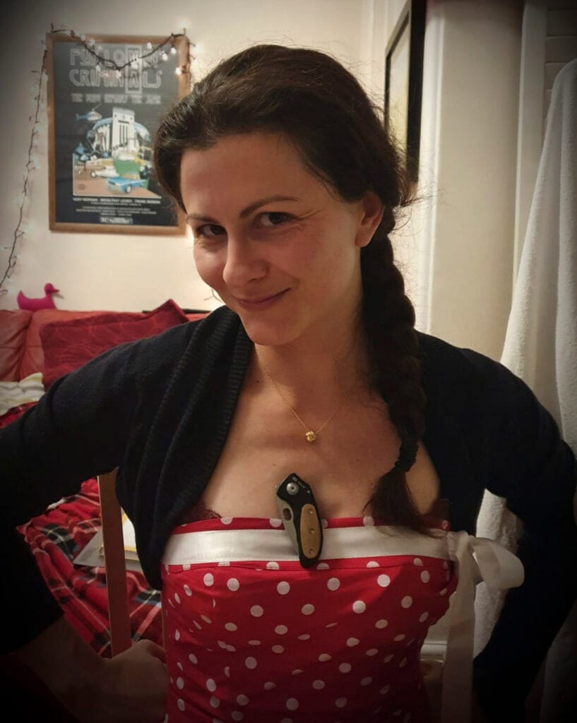 Donna con vestito rosso a pallini bianchi con coltellino in mezzo al seno